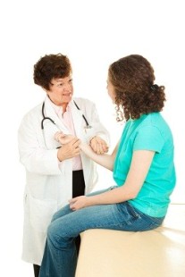 Caring female doctor checking the pulse of her teenage patient. Isolated on white.
