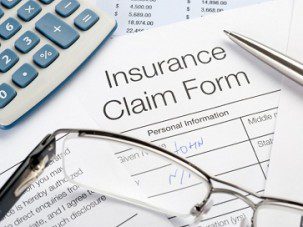 Handwritten Insurance Claim Form with pen and calculator