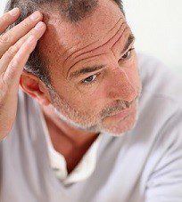 Senior man looking at his hair in mirror