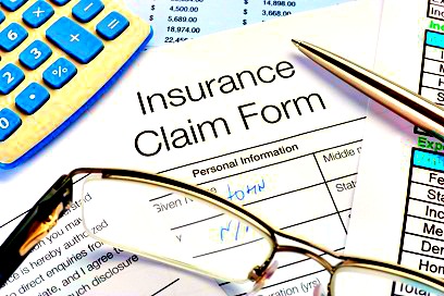 Close up of handwritten Insurance Claim Form with pen and calculator