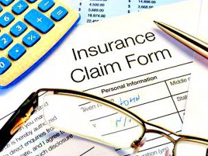 Close up of handwritten Insurance Claim Form with pen and calculator