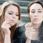 Two sad young girls smoke