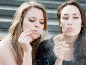 Two sad young girls smoke