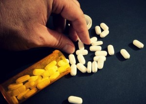 hand picking from prescription pills spilled from bottle
