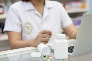 Pharmacist with laptop computer and medication in the pharmacy